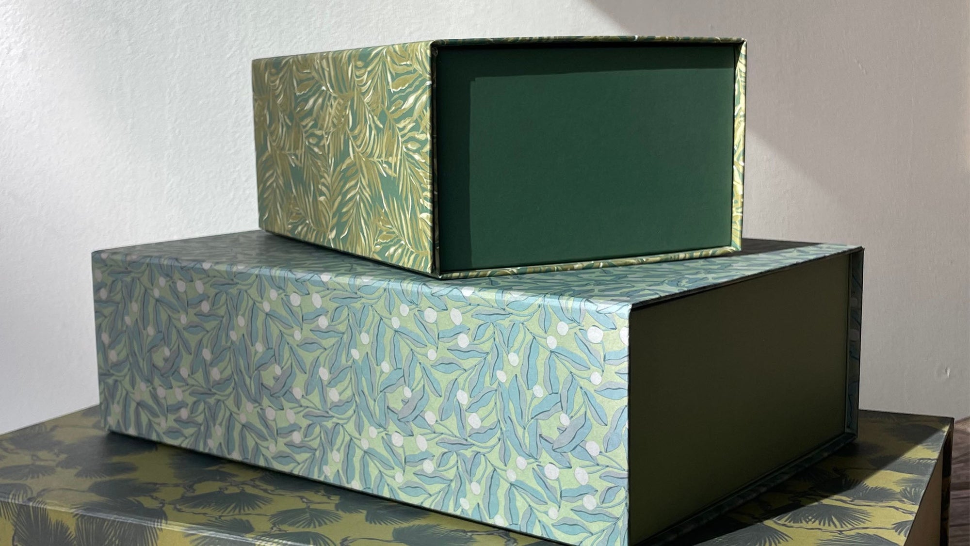 Stacked rectangular desk storage boxes with botanical leaf pattern in green and blue tones, open-front design showing solid green interior