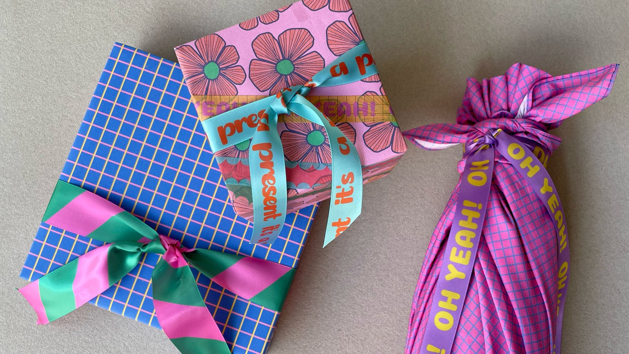 three gift packages wrapped in colourful patterned paper and fabric with decorative ribbons and knots