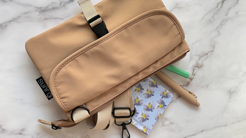 beige small utility pouch with adjustable strap and zipper closure, top view, closed