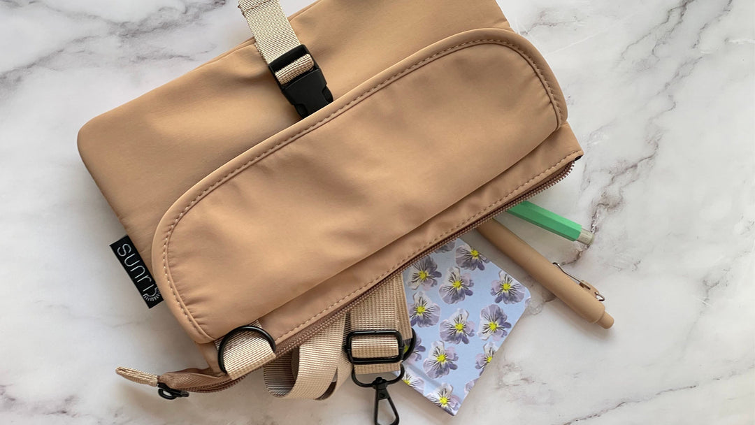 beige small utility pouch with adjustable strap and zipper closure, top view, closed