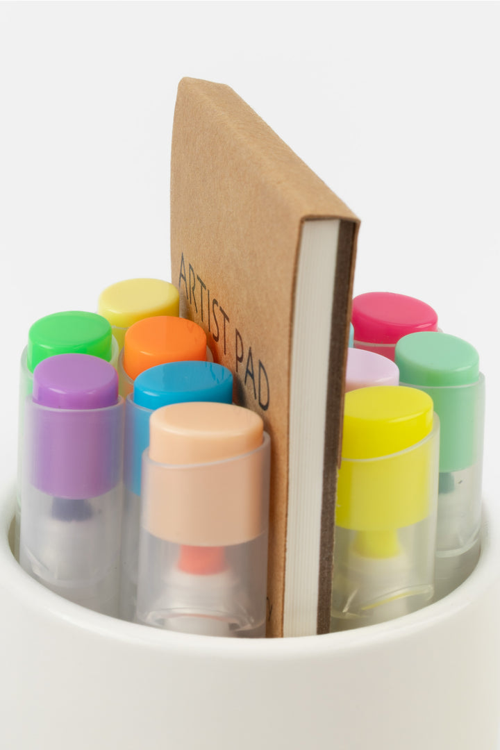 Close-up of open recycled cardboard tube showing the tops of 12 highlighters and the artist pad