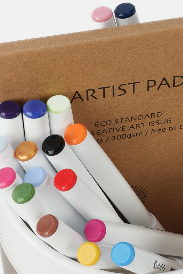Close-up of felt-tip pen tops in assorted colours with the artist pad behind
