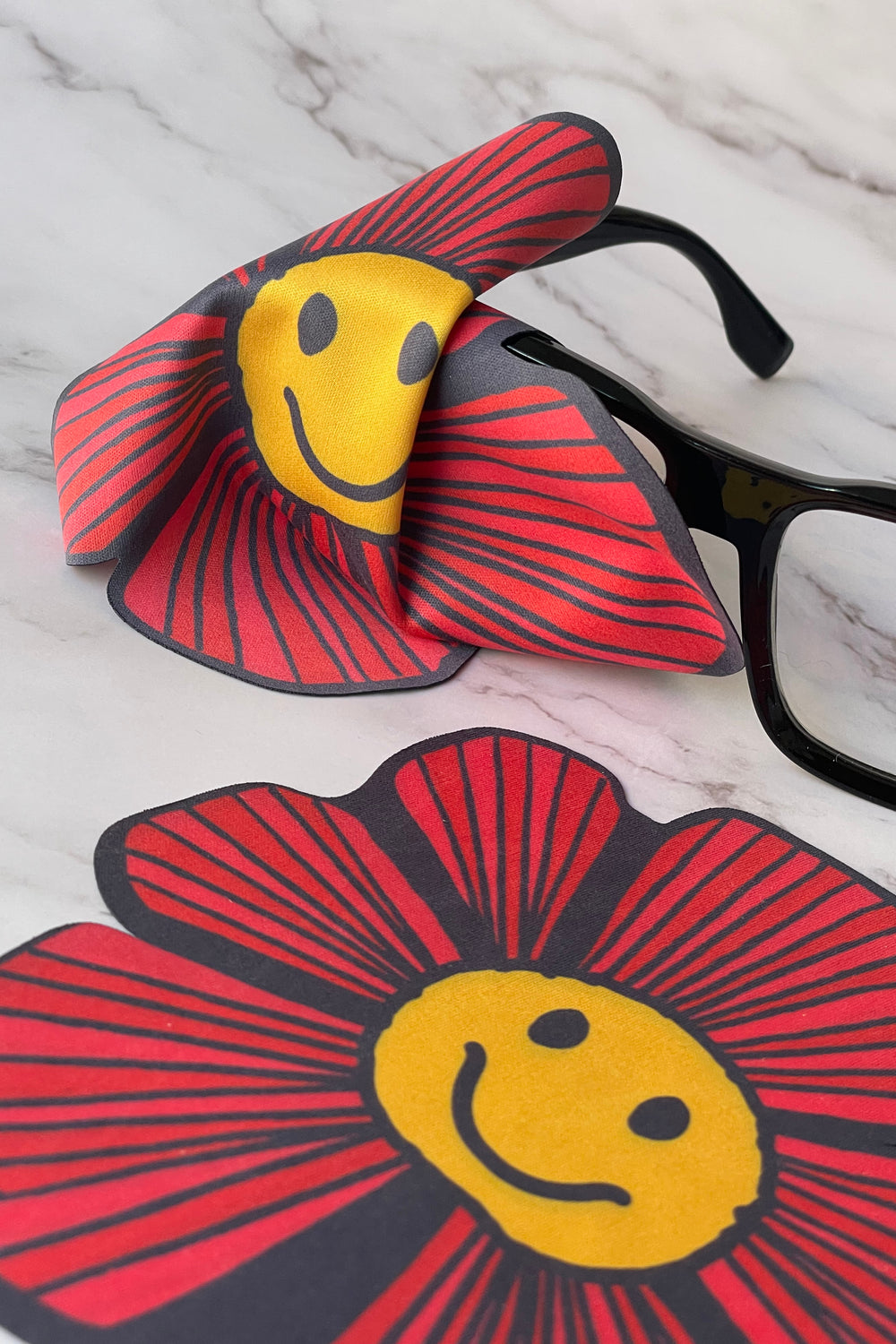 flower-shaped screen wipe shown cleaning a pair of glasses
