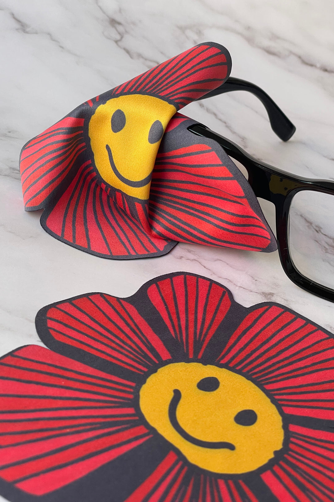 flower-shaped screen wipe shown cleaning a pair of glasses
