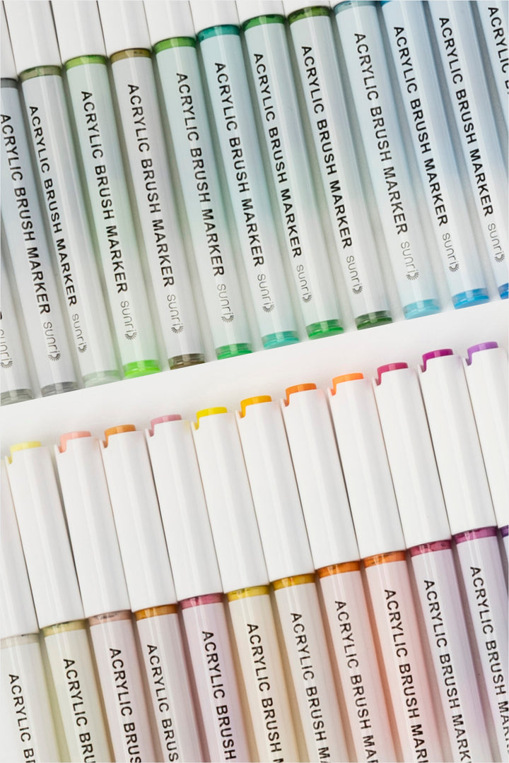 acrylic brush markers arranged flat showing colour range and white barrels
