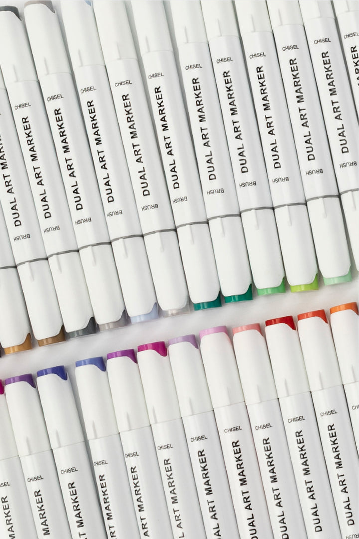 Dual tip art marker with brush tip and chisel tip visible, white body with black brush label and purple caps