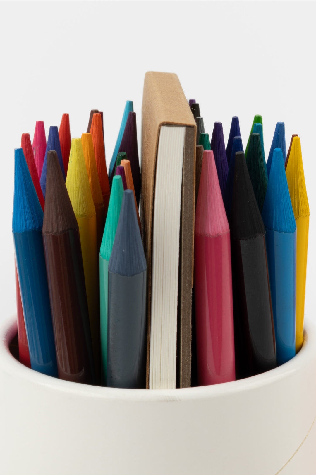 Close-up of woodless aquarelle pencils in assorted colours with the artist pad behind
