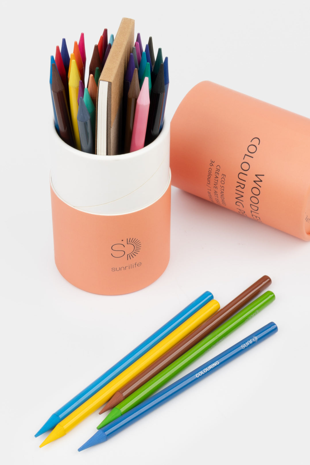 Colorful wooden pencils in a peach-colored holder on a white background