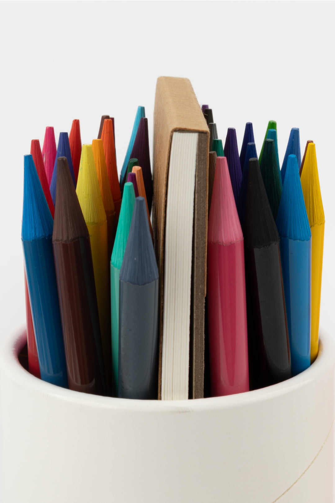 Close-up of woodless colouring pencils in assorted colours with the artist pad behind
