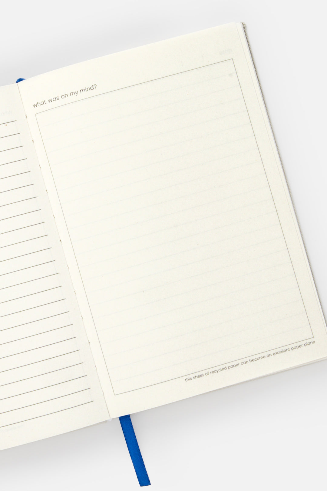 Open A5 diary with lined left page blank framed right page and blue ribbon marker
