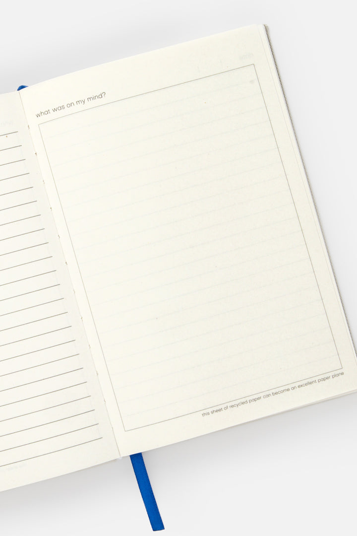 Open A5 diary with lined left page blank framed right page and blue ribbon marker
