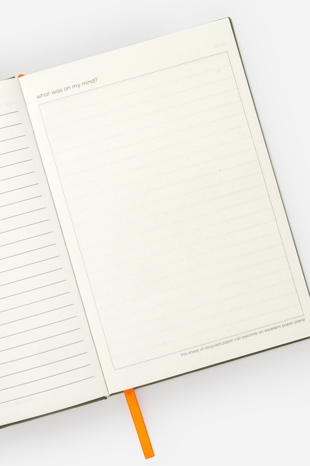 Open A5 diary with lined left page blank framed right page and orange ribbon marker
