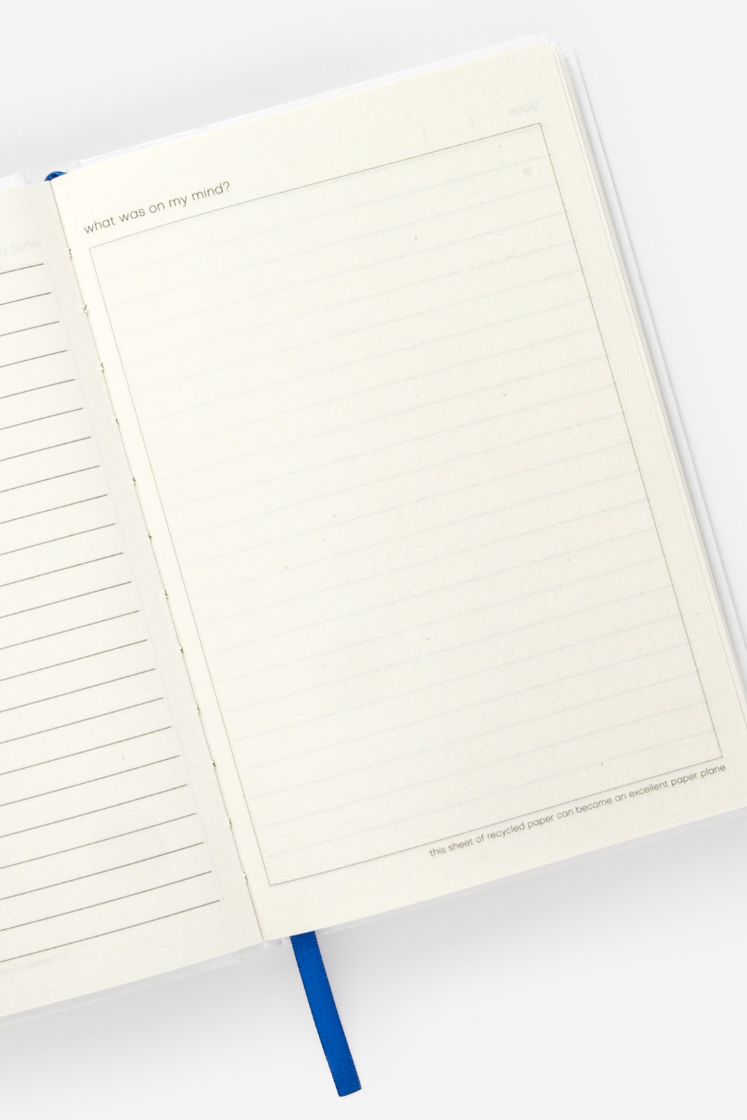 Open diary showing lined left page blank framed right page and blue ribbon marker

