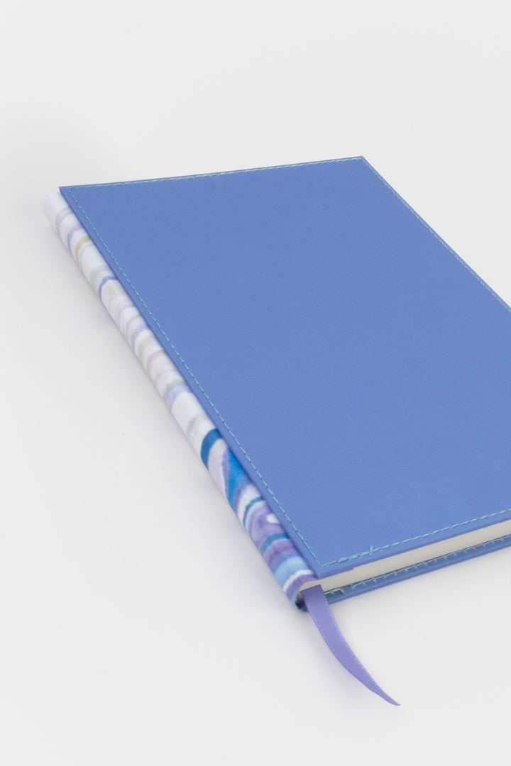planner angled to show the marbled spine and blue stitched fabric cover
