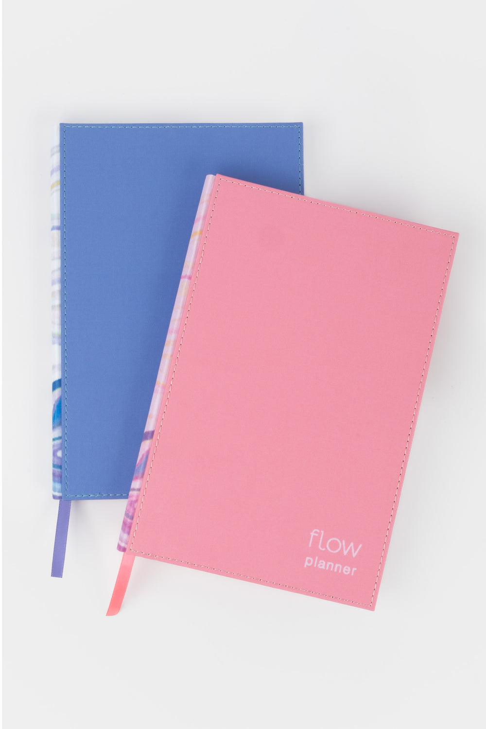 two planners stacked with pink and blue fabric covers and matching ribbon markers
