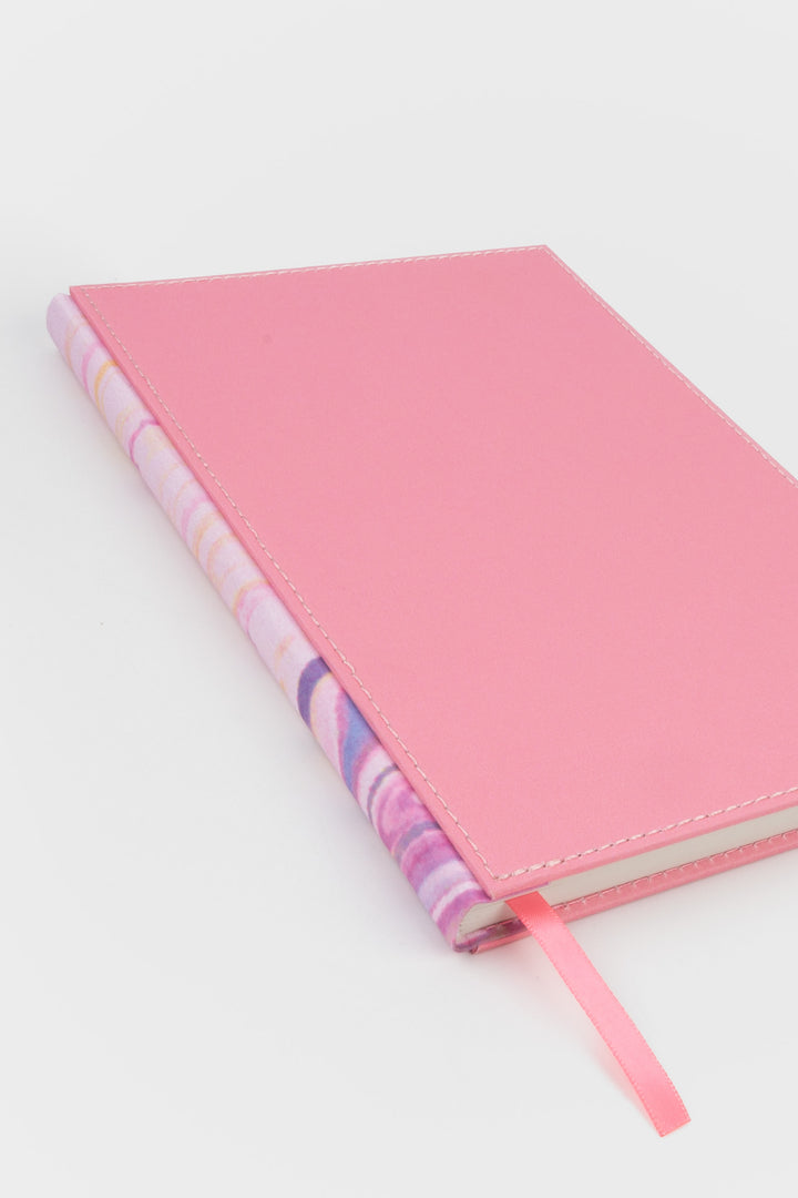 planner angled to show the marbled spine and pink stitched fabric cover
