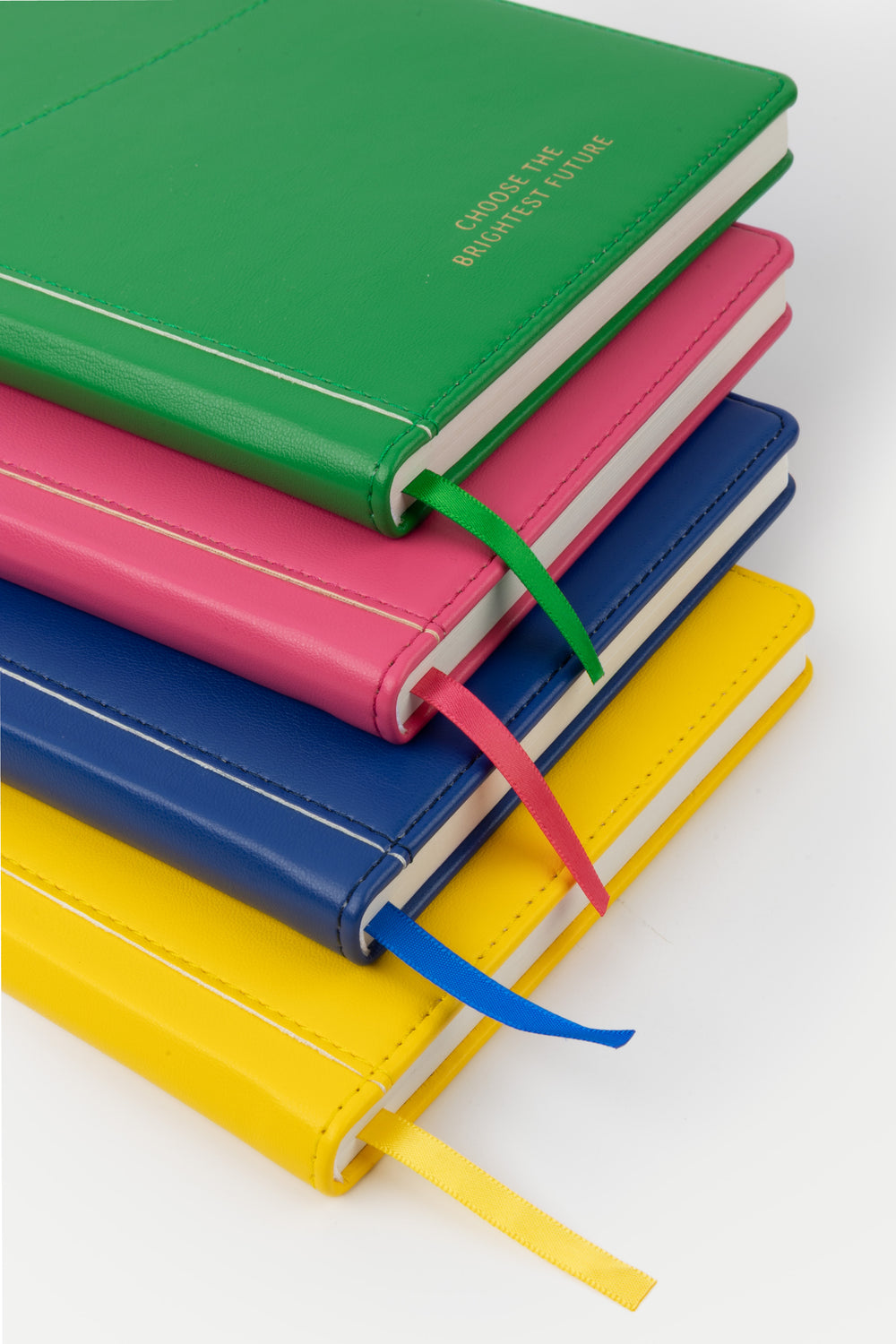 stack of A5 PU leather notebooks in green pink blue and yellow with matching satin markers
