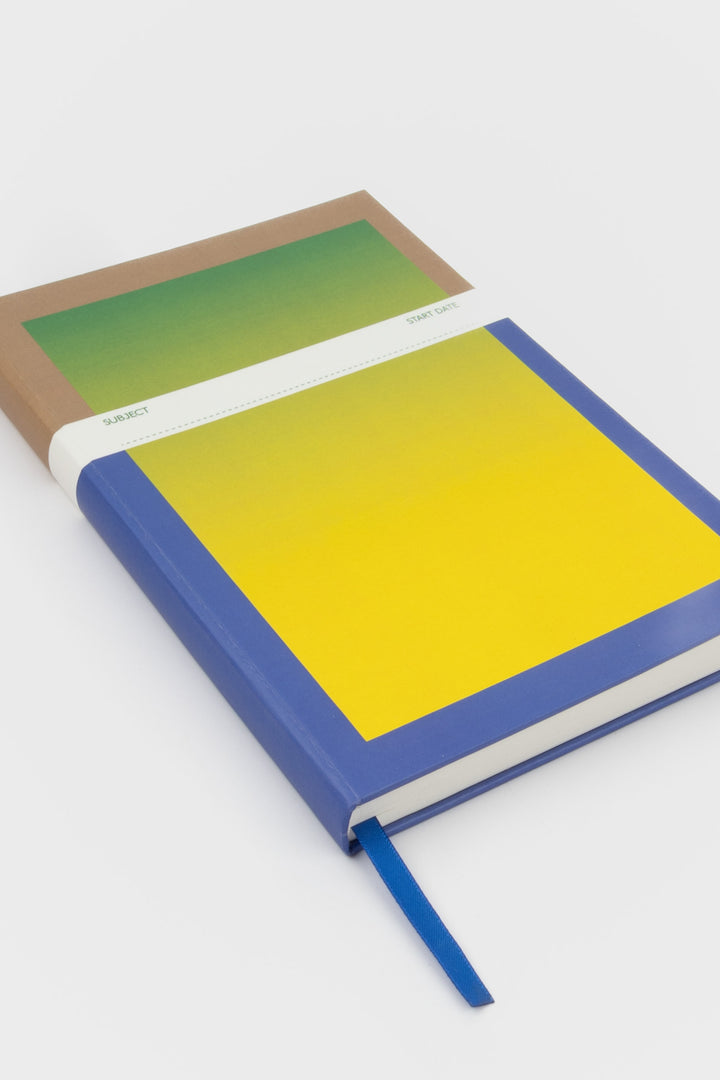 a5 notebook with blue to yellow gradient cover shown at an angle

