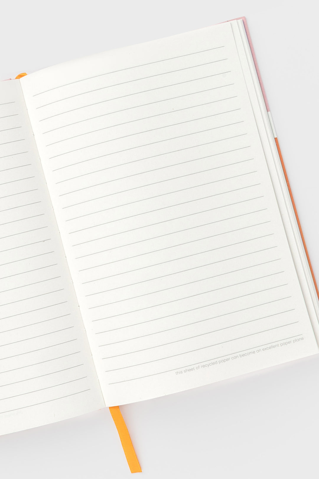 open A5 notebook showing ruled pages with orange satin marker visible
