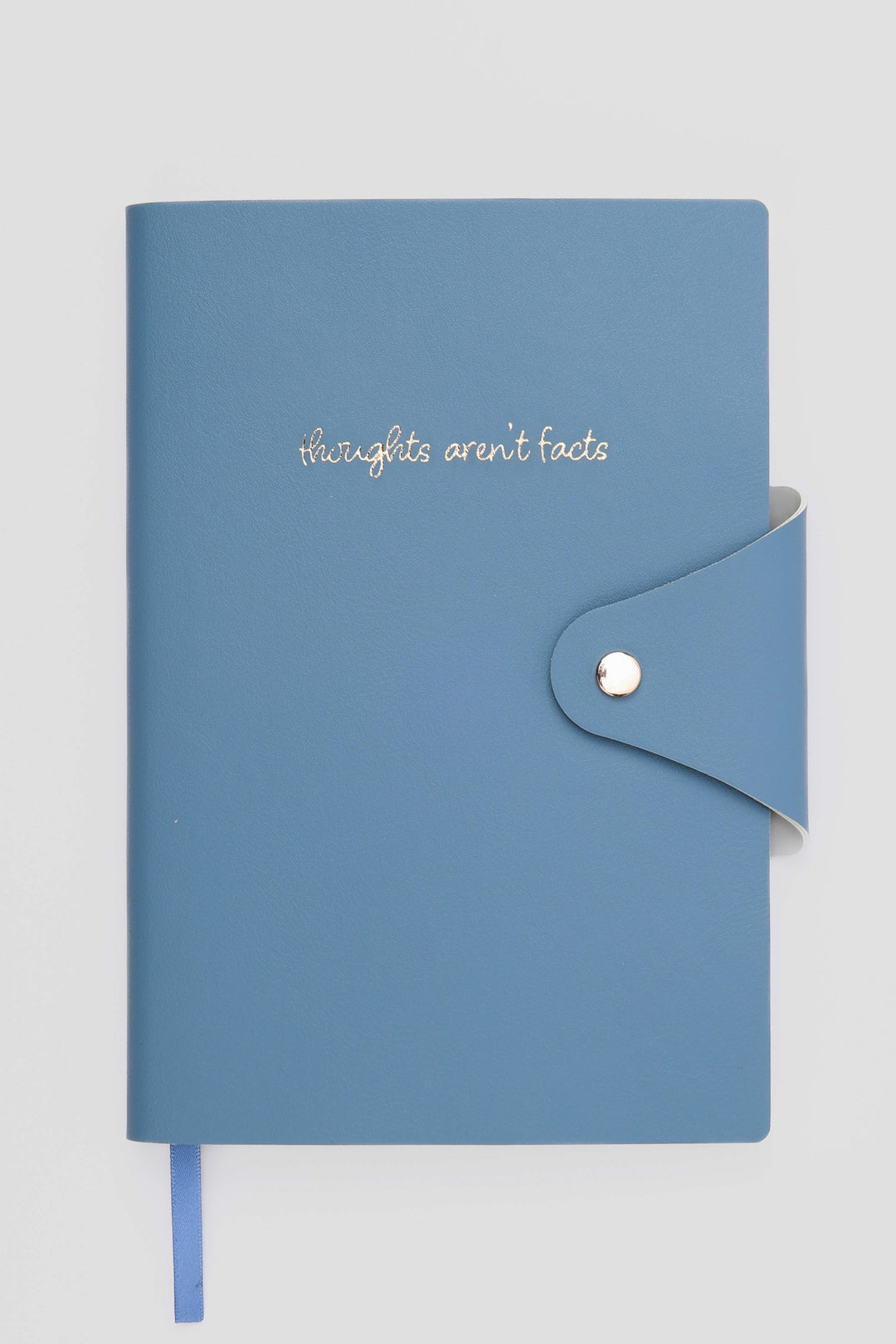 Blue notebook with 'thoughts aren't facts' text on a light gray background
