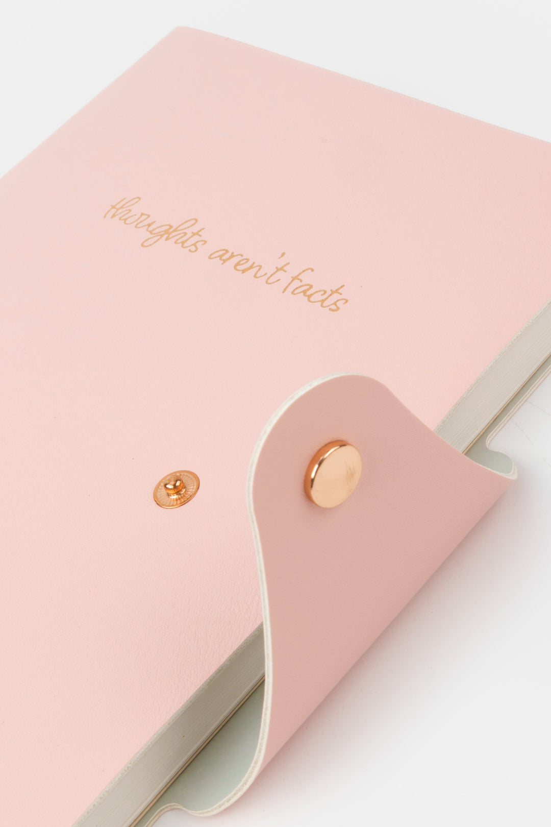 Pink notebook with gold text and buttons on a light background