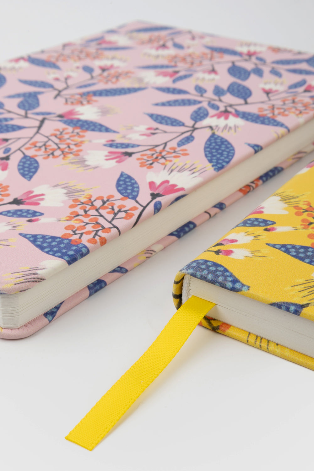 close-up of two notebooks with pink and yellow floral covers and yellow ribbon marker
