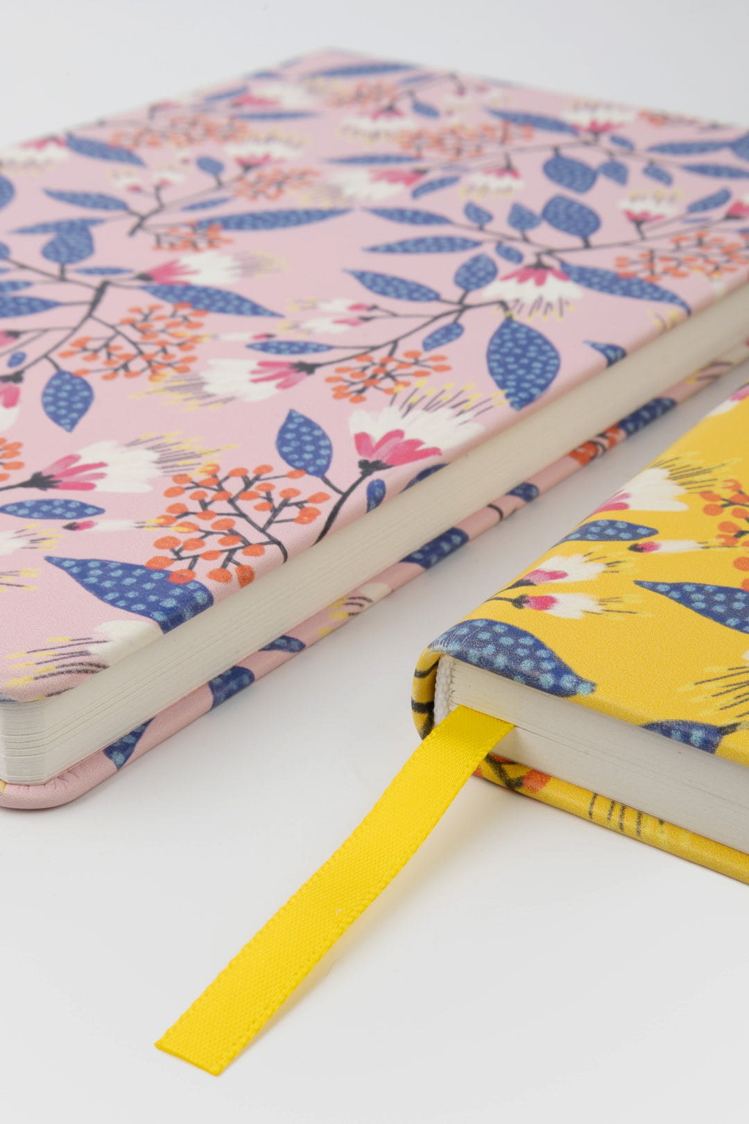 close-up of two notebooks with pink and yellow floral covers and yellow ribbon marker
