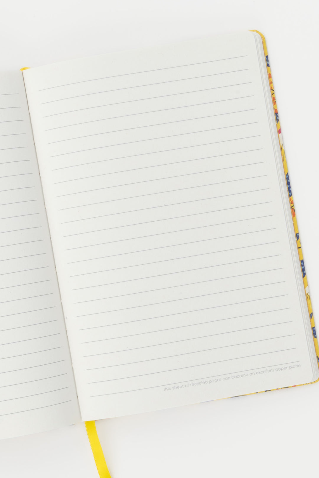 open notebook showing ruled pages with the yellow ribbon marker visible at the bottom
