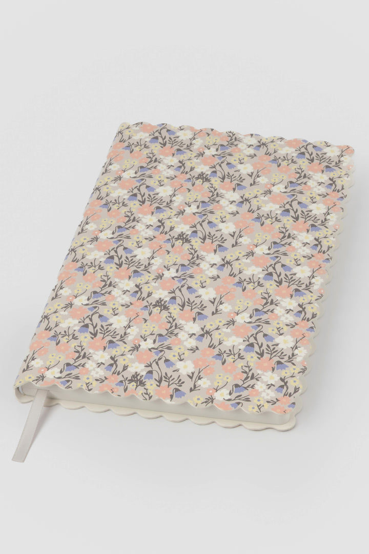 front view of a scalloped-edge notebook with an all-over small flower pattern in pastel colours