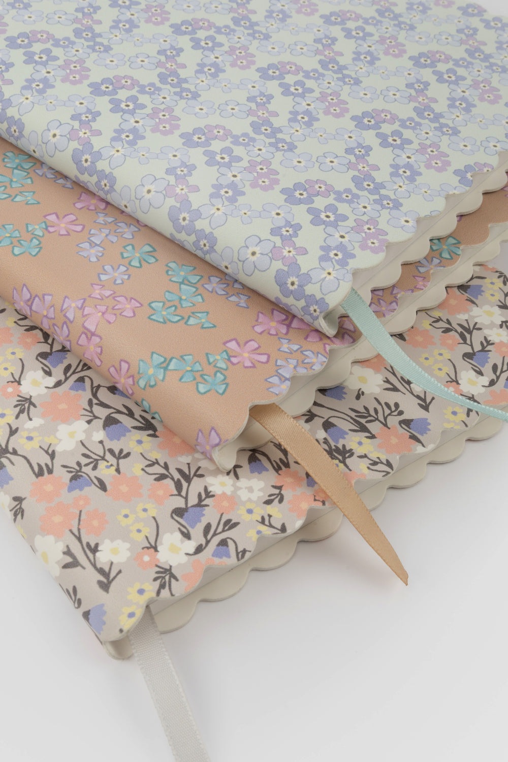 stack of scalloped-edge notebooks with different pastel flower patterns and matching ribbon markers