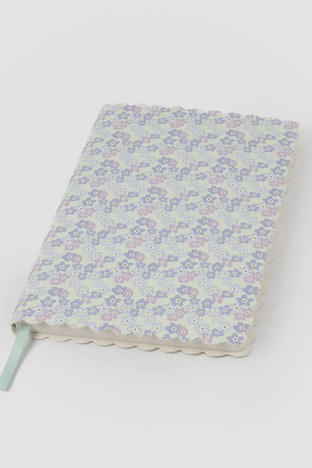 front view of a scalloped-edge notebook with an all-over small flower pattern in pastel colours