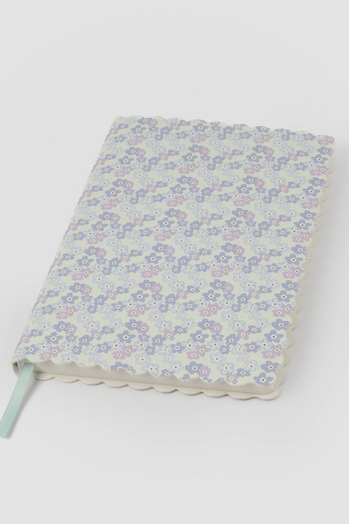 front view of a scalloped-edge notebook with an all-over small flower pattern in pastel colours
