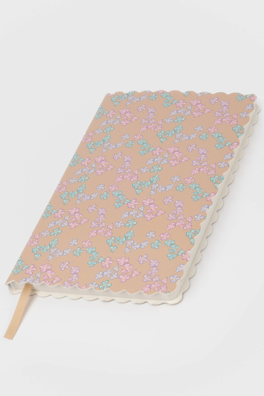 front view of a scalloped-edge notebook with an all-over small flower pattern in pastel colours