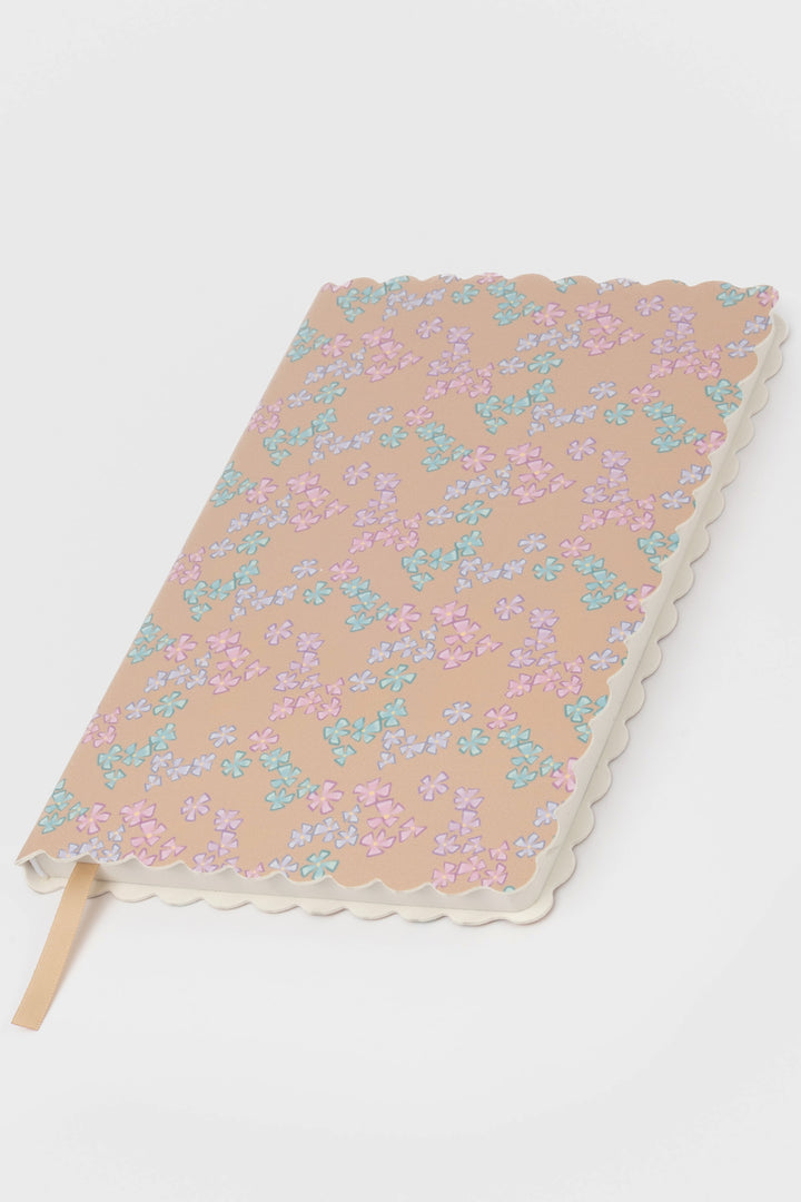 front view of a scalloped-edge notebook with an all-over small flower pattern in pastel colours