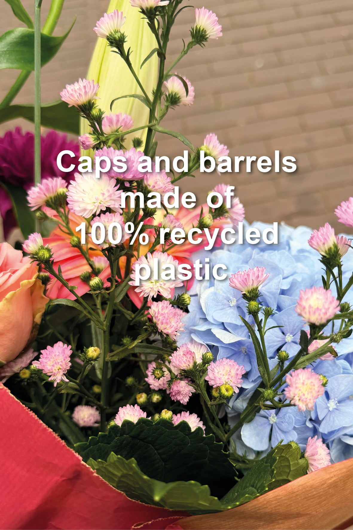 A close-up of a bouquet of flowers with overlaid text reading 'Caps and barrels made of 100% recycled plastic.' The visible product context appears to be a floral arrangement or packaging context rather than a standalone product shot, and no specific sellable item is clearly isolated.