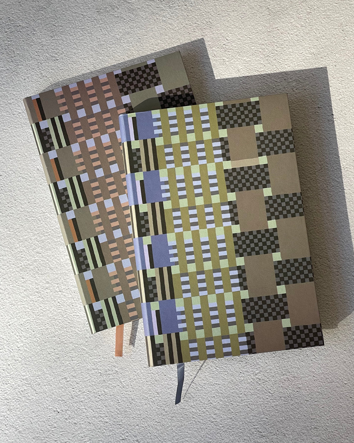 two notebooks with grapgic print on cover on a grey background