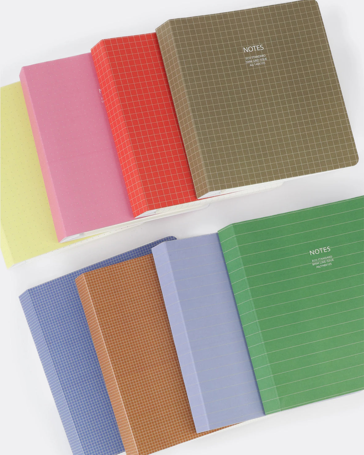 Six notebooks arranged in two overlapping stacks on a white background. The top stack includes a pale yellow notebook, a pink notebook with a red grid pattern, and a brown grid-patterned notebook labeled NOTES.