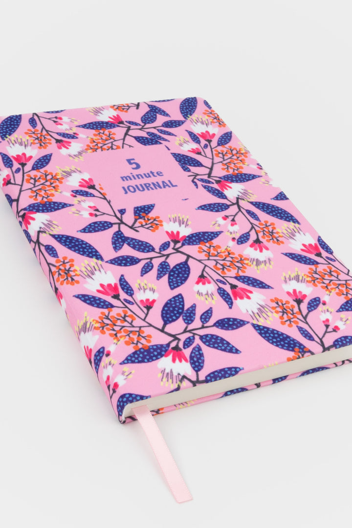 angled view of a5 five minute journal with pink floral fabric cover and ribbon marker
