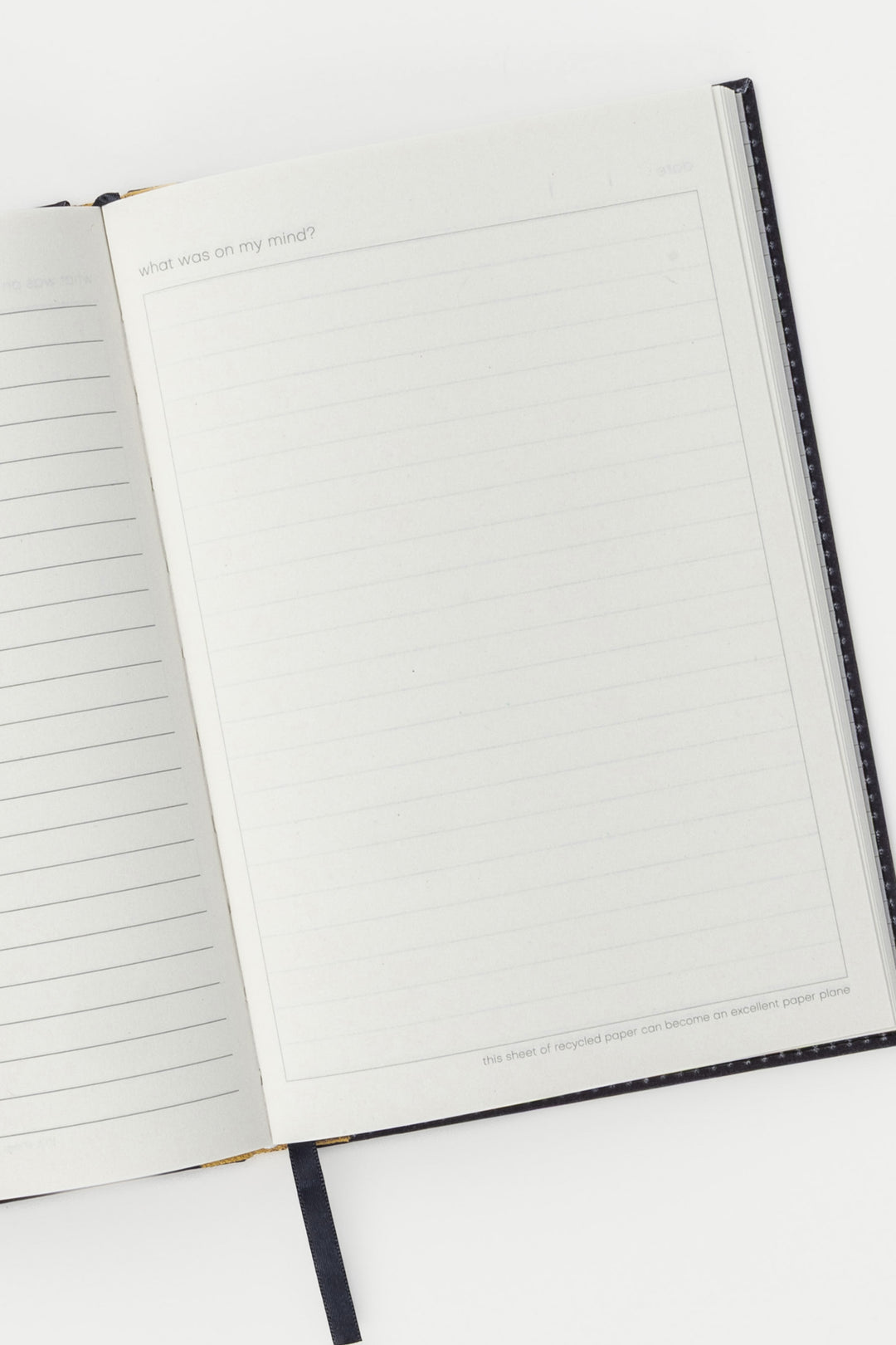 Open A5 diary showing lined and blank recycled paper pages with ribbon bookmark