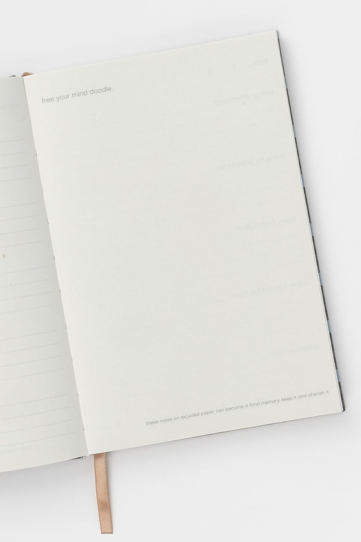 Open A5 journal showing lined and blank recycled paper pages with ribbon bookmark visible