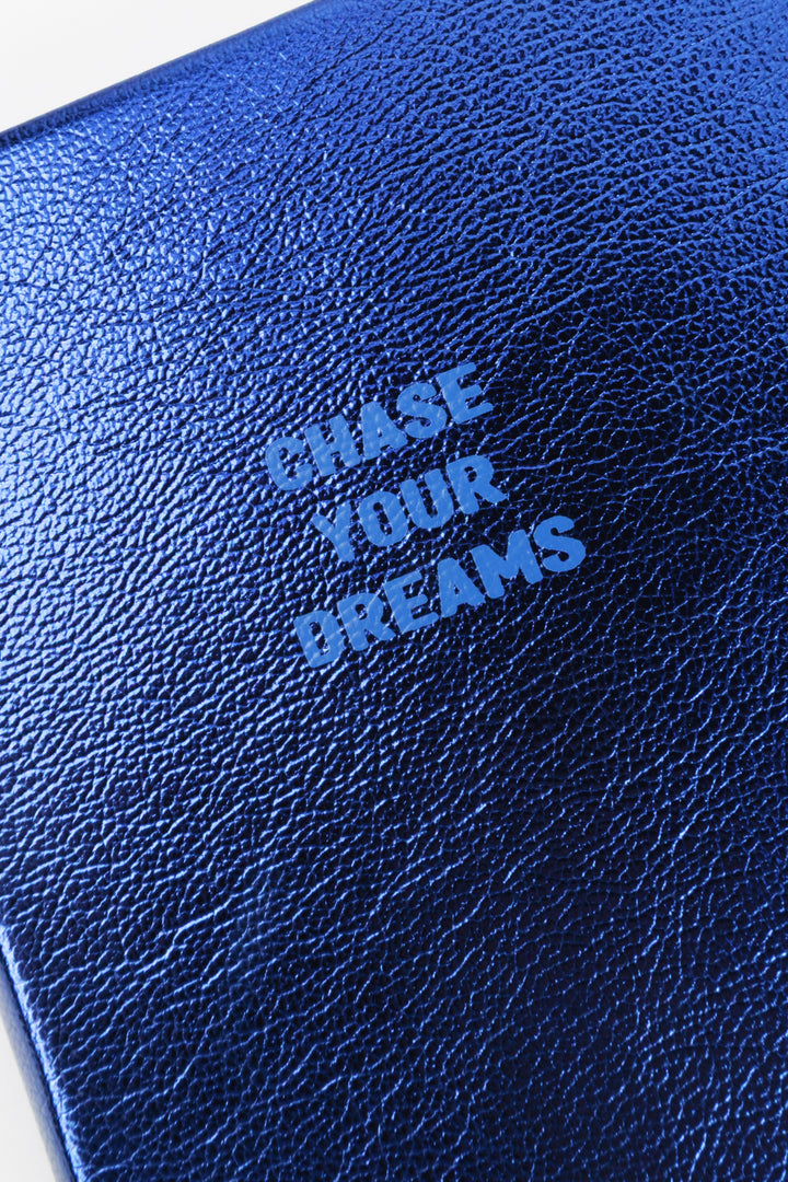 Close-up of blue metallic cover texture with chase your dreams text

