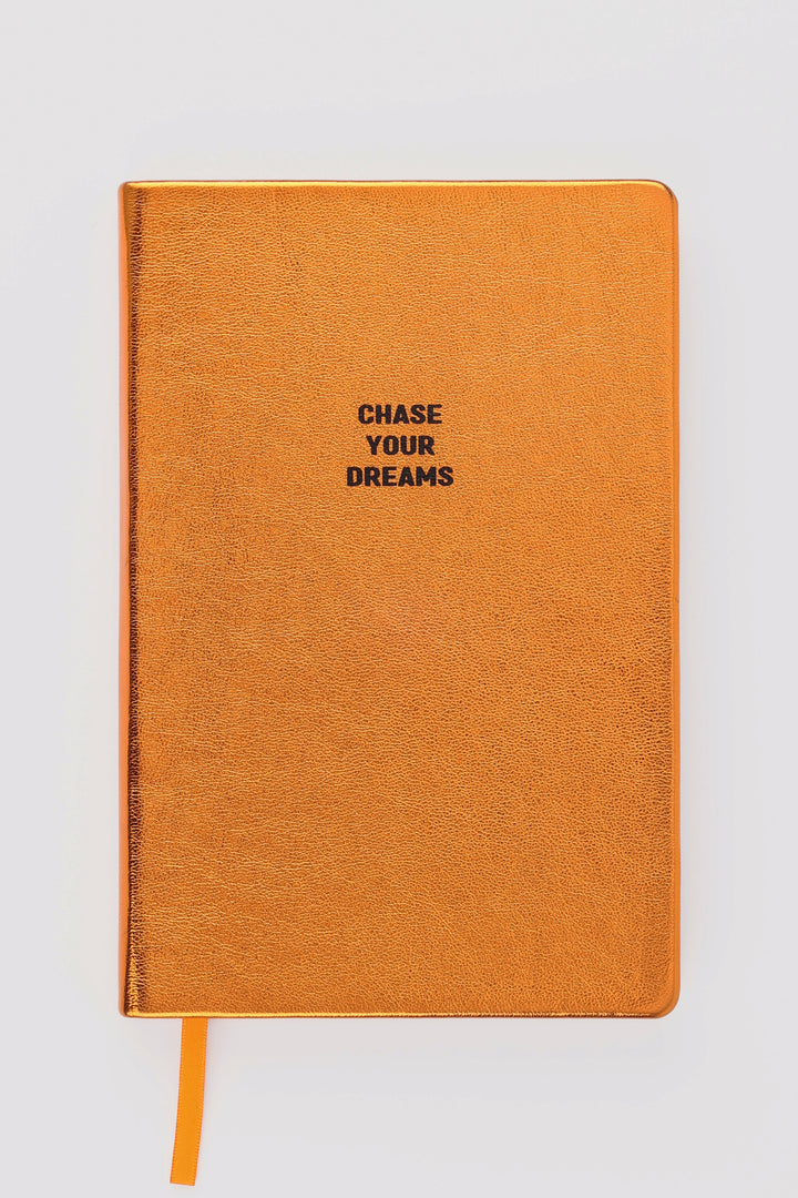 Closed orange metallic A5 notebook with chase your dreams text and orange ribbon marker

