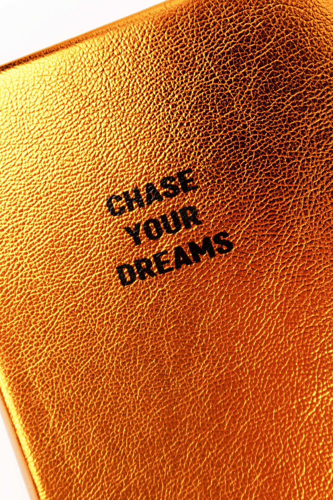 Close-up of orange metallic cover texture with chase your dreams text
