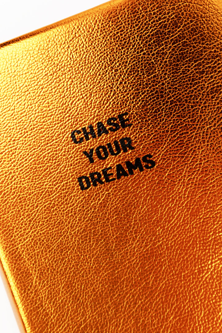 Close-up of orange metallic cover texture with chase your dreams text
