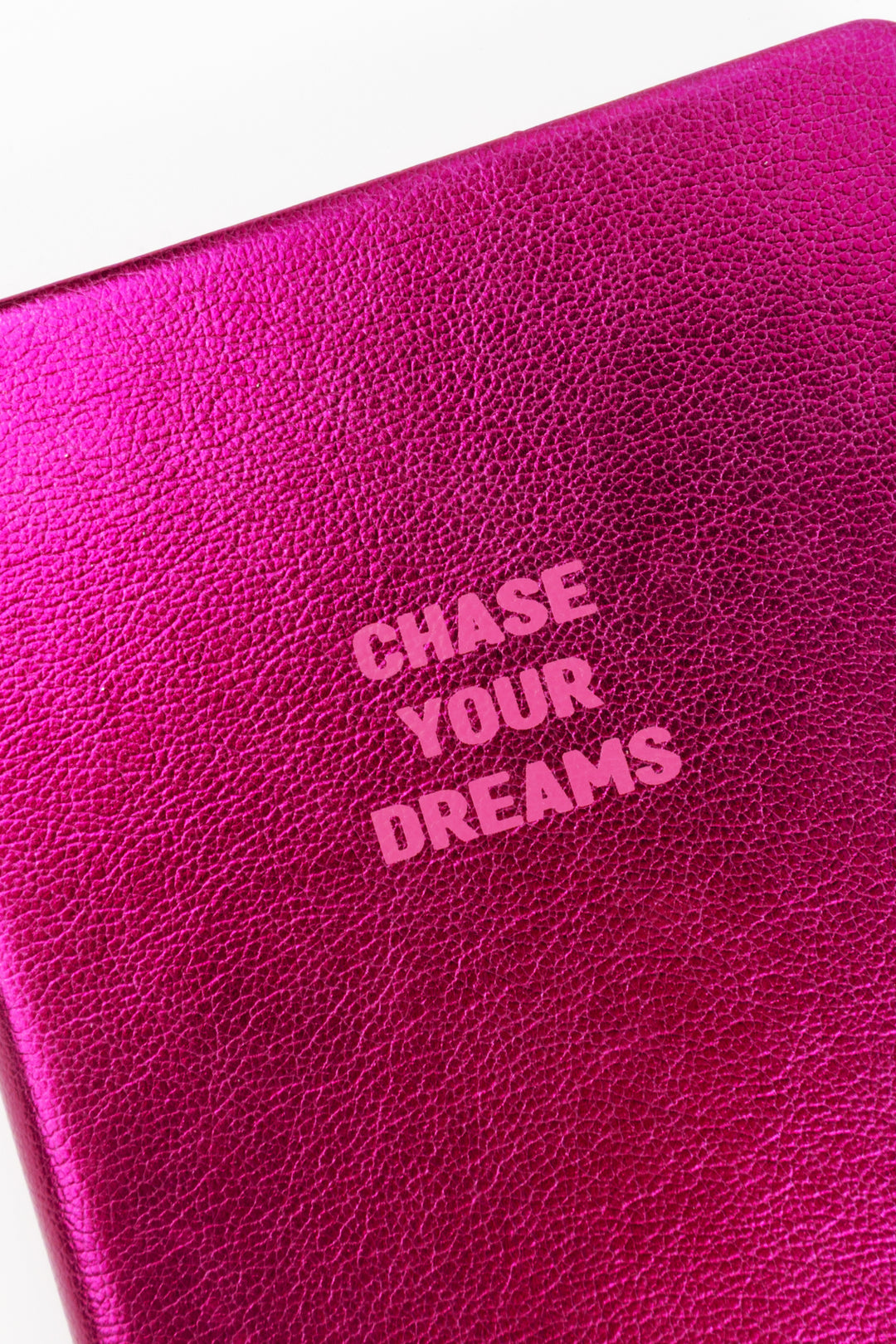 Close-up of pink metallic cover texture with chase your dreams text
