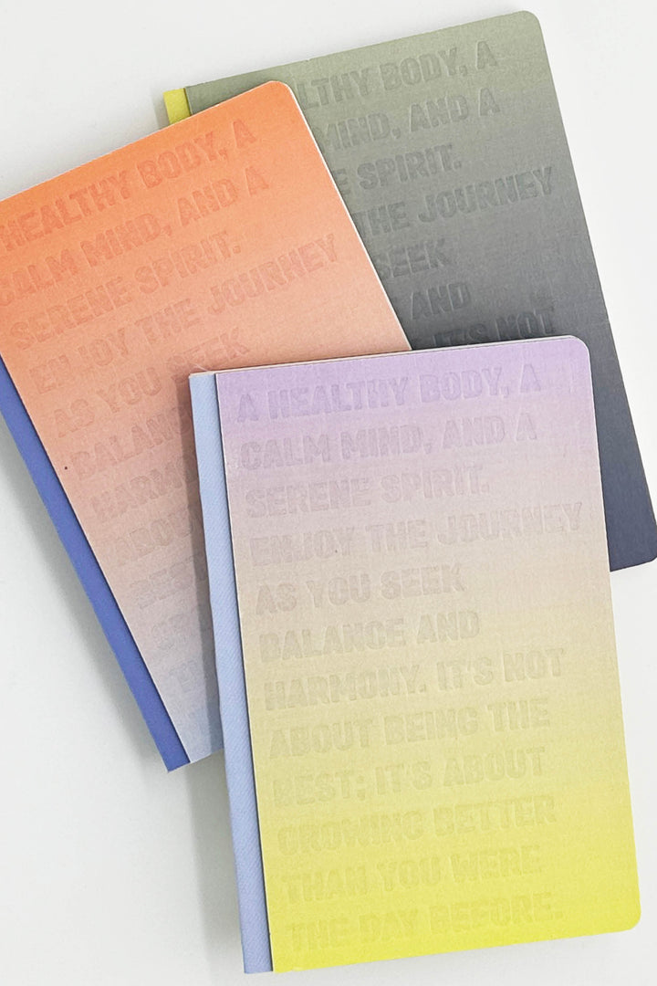 Three gradient notebooks in orange, gray, and purple on a white background