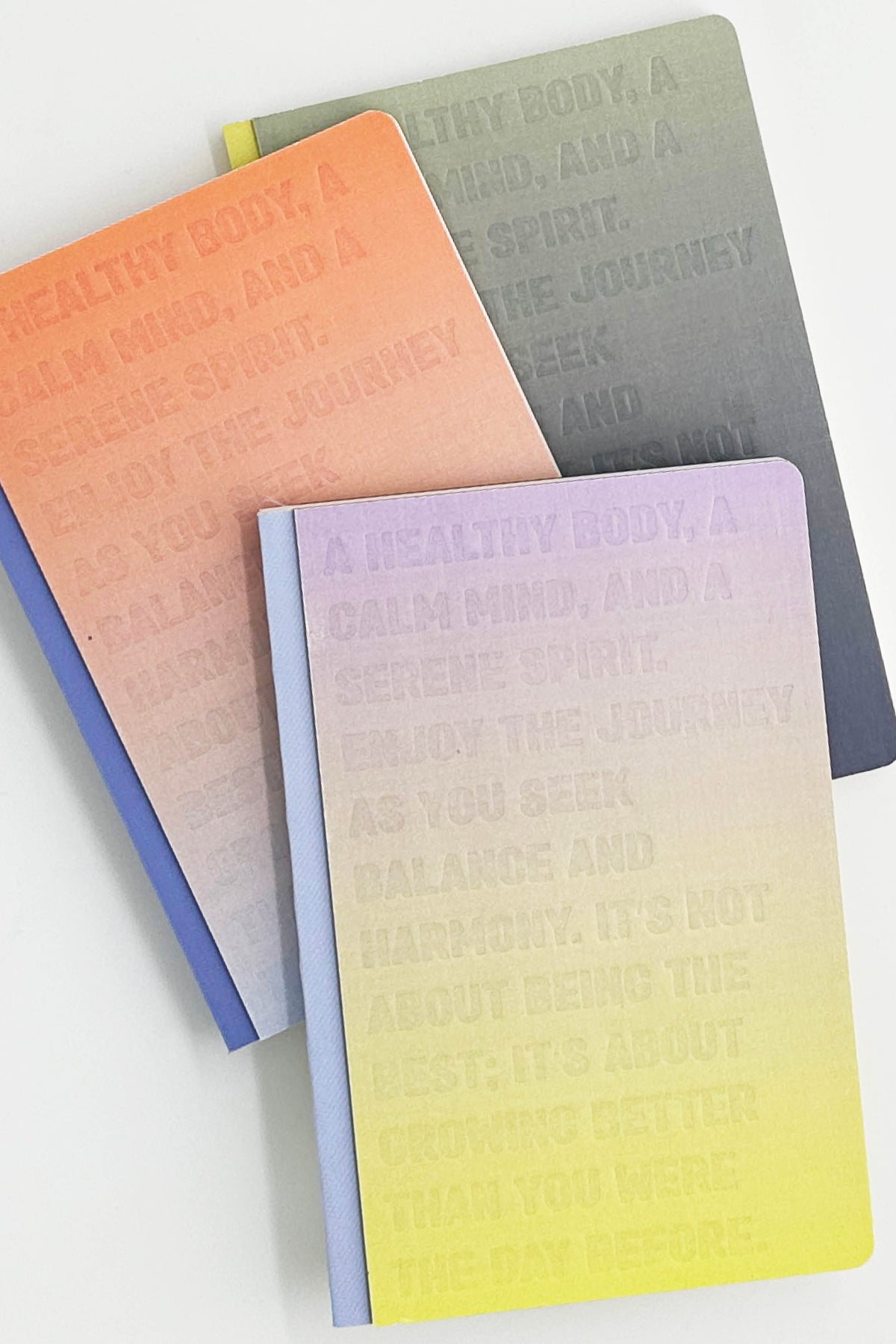Three gradient notebooks in orange, gray, and purple on a white background