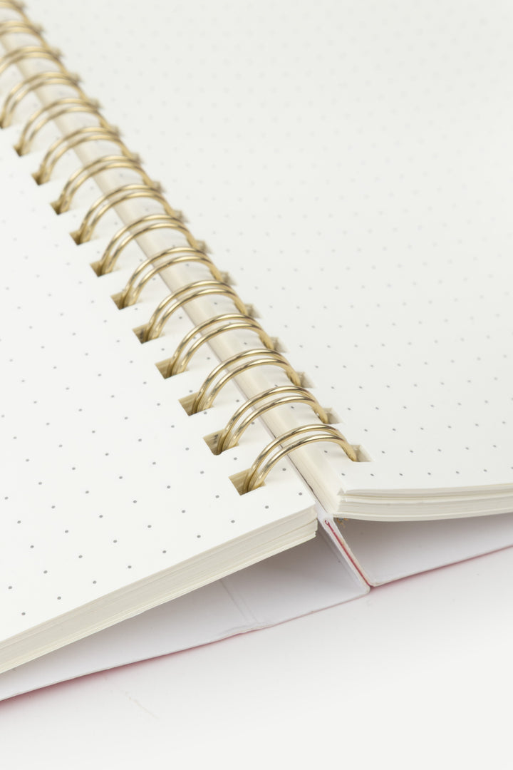 Close-up of a spiral-bound notebook with dotted white pages 