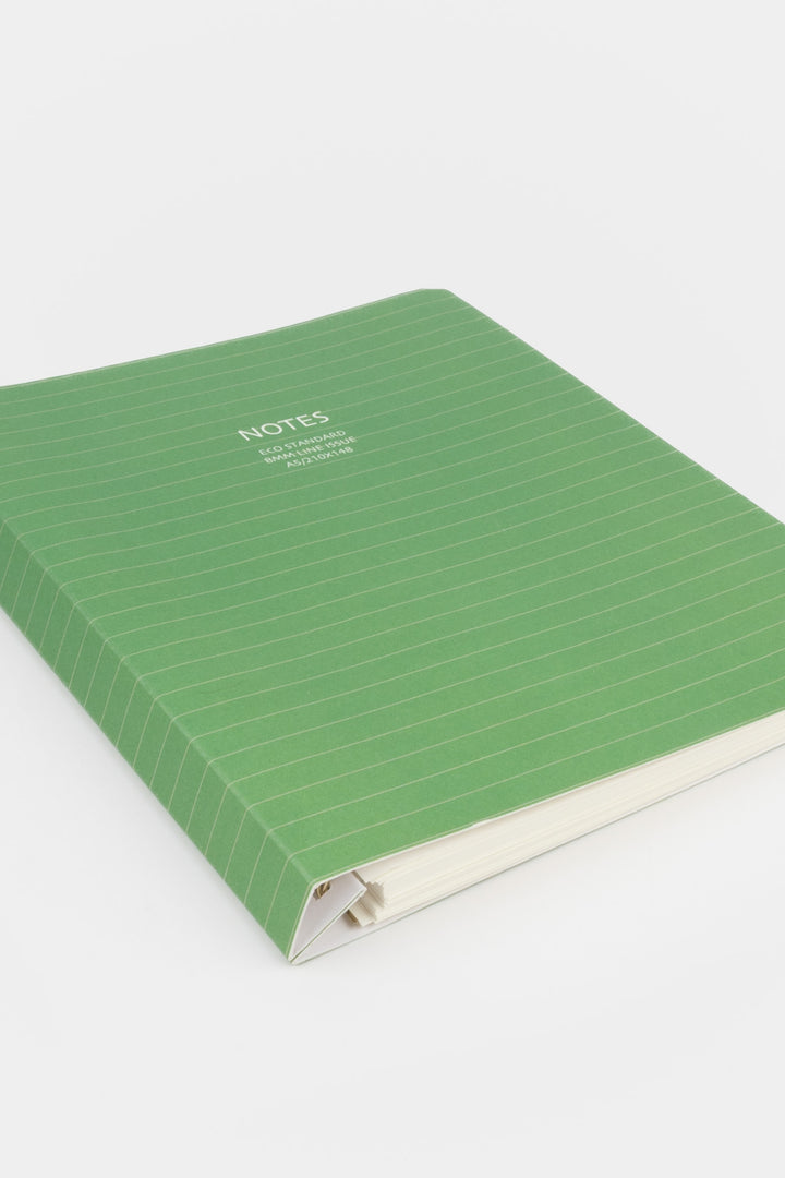 green A5 notebook with lined green cover photographed from a low angled side view
