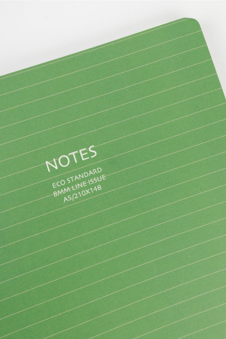 close-up of green A5 notebook cover with white notes eco standard text and horizontal lines
